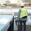 Two people in yellow vests and construction hats look at a pool.