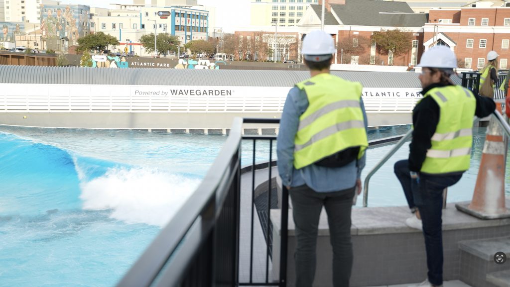 Two people in yellow vests and construction hats look at a pool.